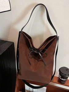 Brown faux suede shoulder bucket bag with black leather bow and wide strap detail