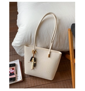 Detail of cream oil wax leather tote with wood bead tassel in cozy home setting