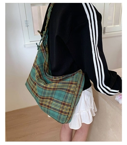 Detailed view of large green tartan hobo bag worn by person in casual setting