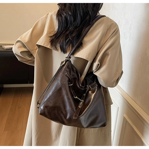 Detail of dark brown glossy hobo bag side buckle and leather texture on a shoulder bag