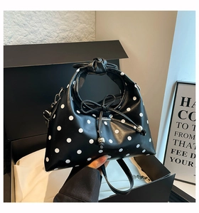 Close-up of retro polka dot dumpling bag with knotted handle and bow drawstring detail