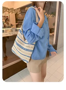 Detail view of woven hollow tote bag with blue stripes held by model in casual outfit