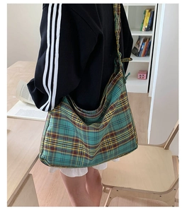Green and yellow plaid canvas tote bag with knotted shoulder strap worn by a model