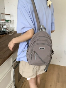 Minimalist taupe nylon sling backpack with multi-layer zipper compartments for casual travel