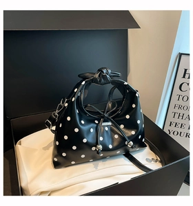 Detail view of polka dot crossbody bag in black leather with knot handle and silver hardware