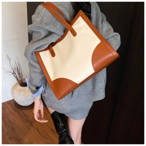 Détail du grand sac cabas en toile avec garniture en cuir porté à l'épaule