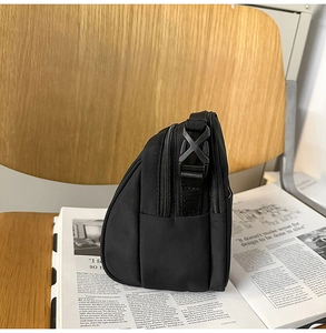 Detalle del bolso bandolera de nailon que muestra las cremalleras dobles y hebillas laterales