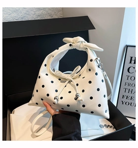 Detail view of polka dot handbag featuring a knotted handle and metal bead bow decoration