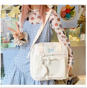 Detail showing white ita bag with heart-shaped clear window and blue bow embroidery