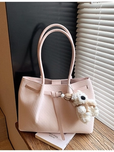 Sac fourre-tout rose à texture tressée avec breloque ours sur un rebord de fenêtre