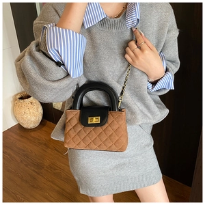 Detail of a brown quilted crossbody bag with golden turn-lock and elegant chain strap