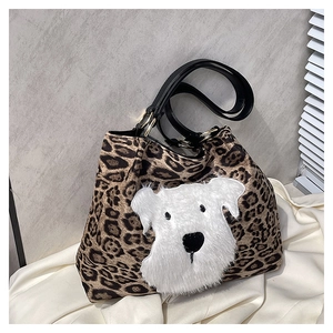 Detail of leopard print tote bag with plush dog patch and black leather handles