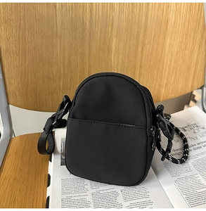 Detalle del bolso bandolera ligero de nailon negro con correa tejida en dos tonos