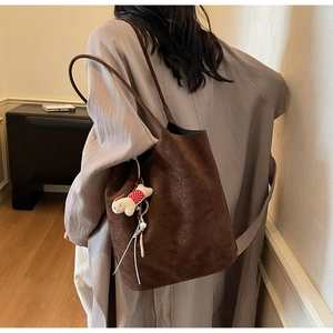 Close-up of deep brown suede bucket bag with a cute puppy plush charm for work