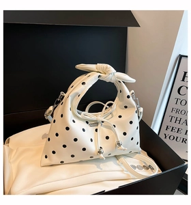 Close-up of white polka dot bag with knotted handle, drawstring, and silver metal bead details
