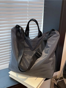 Waterproof grey nylon tote bag with black handles and adjustable shoulder strap for travel