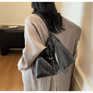 Detailed view of black leather hobo bag showing fine texture and golden metal hardware
