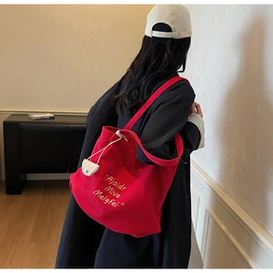 Detailed shot of large red canvas tote bag with letter print and white button pouch charm