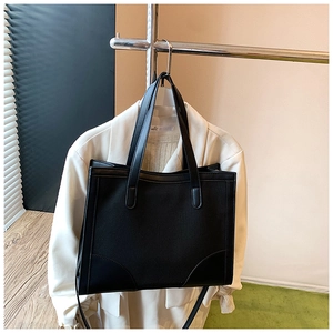 Détail du sac fourre-tout en toile noire avec coins en cuir renforcés et bandoulière