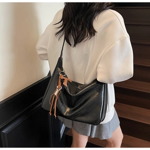 Detalle del bolso hobo de cuero encerado negro con accesorio marrón en una escalera