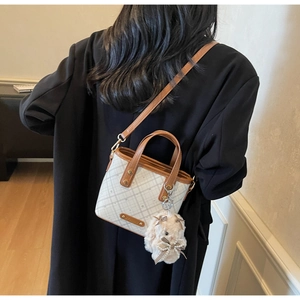 Detailed back view of a mini plaid bucket bag with brown straps and plush rabbit charm