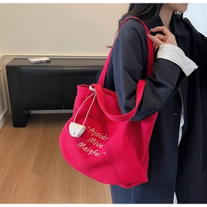 Detailed shoulder view of a large magenta canvas tote bag with white art lettering