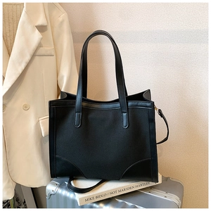 Détail d'un grand sac cabas en toile noire sur une valise argentée dans un cadre chic