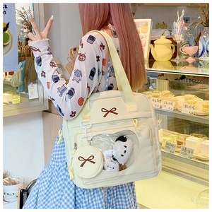 Detail of crossbody bag featuring a heart window, bow accent and matching coin purse