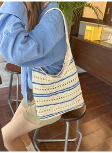 Detail of hand-crocheted cream tote bag with navy blue stripes and hollow weave pattern