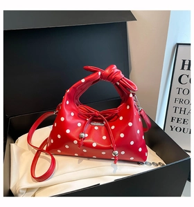 Detail of red polka dot handbag with knot handle, bow and beads in a gift box