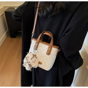 Detail of colorblock bucket bag with brown plaid print and plush rabbit pendant charm
