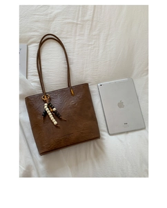 Macro shot of brown retro faux leather tote bag with stylish beaded pendant detail