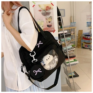 Detail view of black canvas ita bag with clear window, bow detail, and matching coin purse