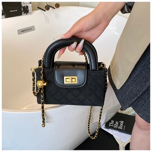 Detail view of black quilted crossbody bag with gold chain strap and metal clasp