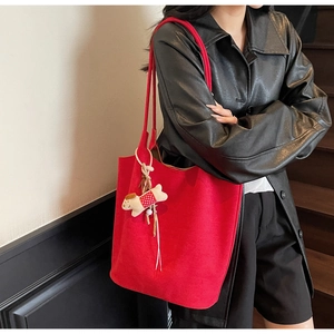 Detail of red large tote bag with cute dog charm on a leather jacket model