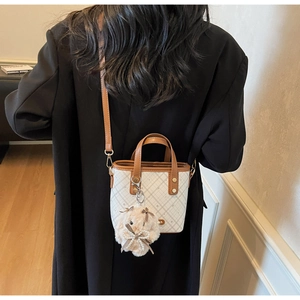 Detail of color-block bucket bag with grid pattern and plush bunny charm on model