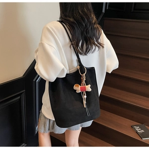 Detail of matte black tote bag showing soft suede texture and cute puppy charm accessory