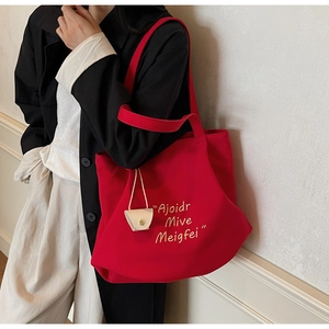 Detail of red canvas tote bag with letter print and decorative white triangle coin purse