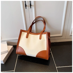 Vue détaillée d'un grand sac fourre-tout en toile avec finitions en cuir marron et anses