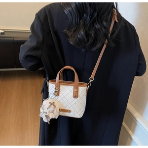 Detailed view of mini contrast water bucket bag with leather trim and plush rabbit charm