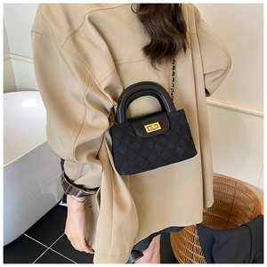 Detail of black quilted crossbody bag with gold twist lock and elegant chain strap