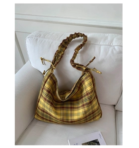Detail of yellow plaid tote bag featuring ruffled shoulder strap and drawstring accents
