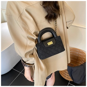 Quilted black chain bag with gold twist lock and circular handle on khaki blazer style