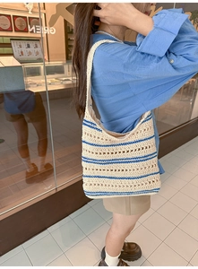 Detailed close-up of handmade crochet hobo bag with blue stripes and hollow knit texture