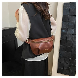 Dettaglio di una borsa a tracolla vintage marrone scuro indossata da una modella in interni