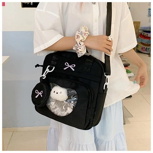 Detail view of black canvas crossbody bag with heart-shaped window and small round pouch