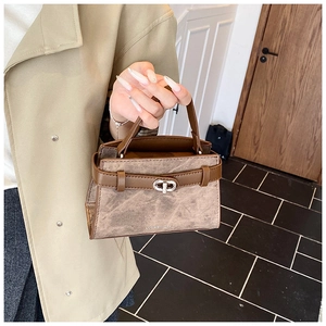 Detail of camel brown vintage crossbody bag featuring crackle texture and silver twist lock