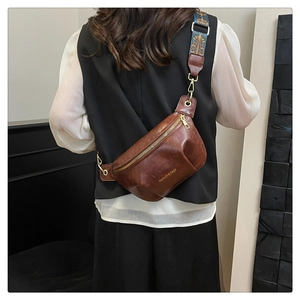 Dettaglio della borsa vintage marrone con ampia tracolla a motivi bohémien decorati