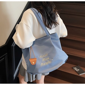 Detail of grey-blue canvas tote bag with yellow embroidery on casual outfit