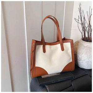 Détail d'un grand sac cabas bicolore en toile beige avec finitions en cuir marron